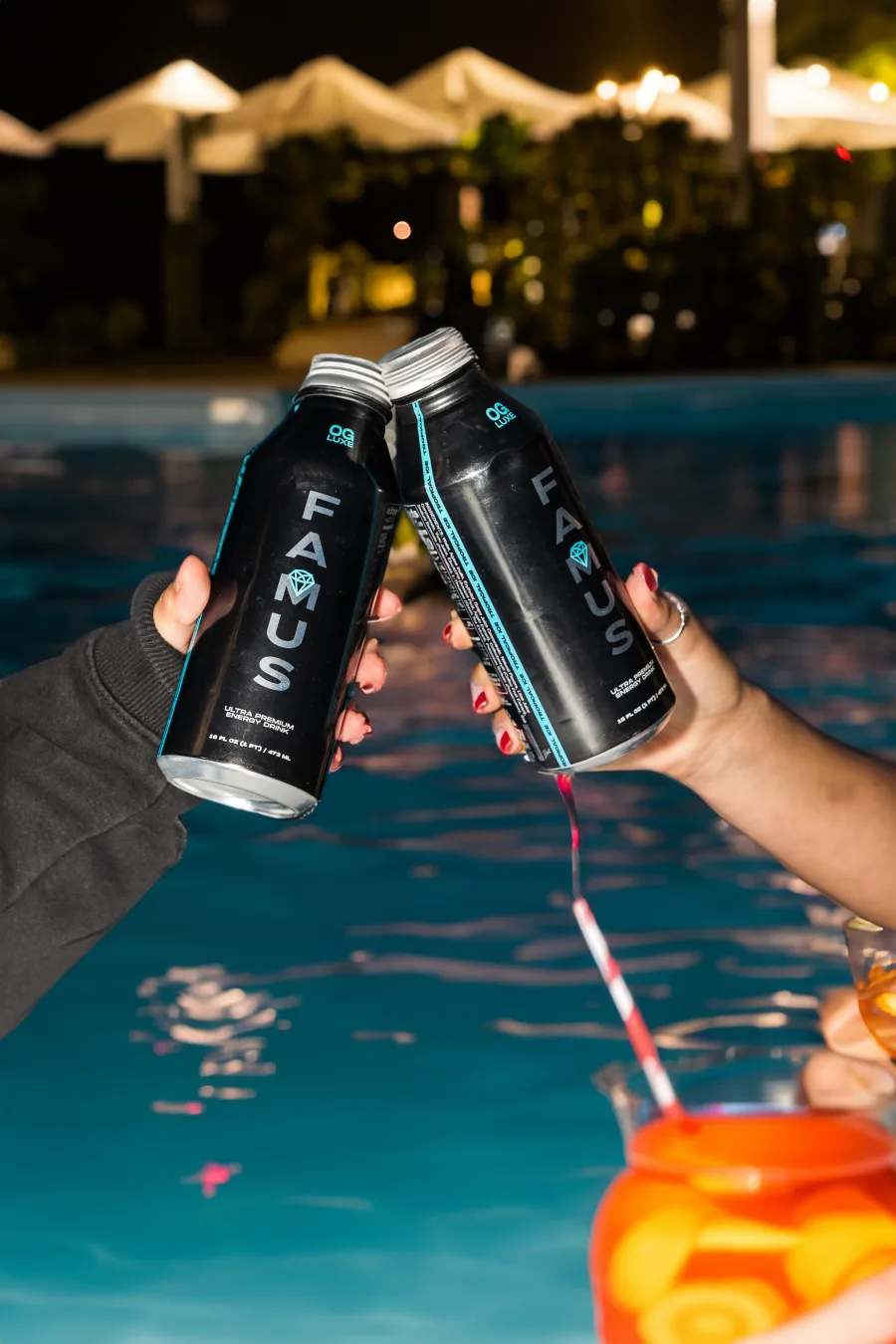 Illustrative scene of hands clinking OG Luxe bottles beside a pool at night